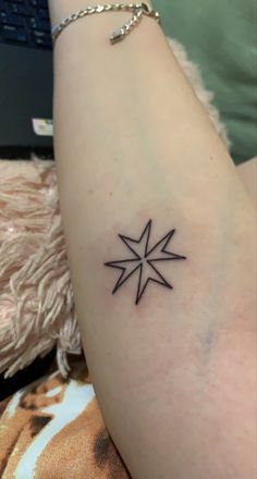 a small black star tattoo on the arm