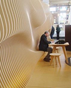 a man sitting at a table in front of a wall with wavy lines on it