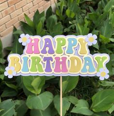 a happy birthday sign sitting on top of a wooden stick in front of some bushes