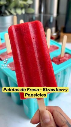 a hand holding a popsicle in front of some plastic containers