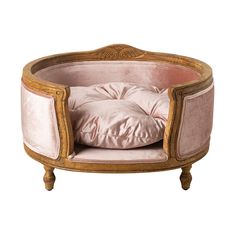 an oval shaped dog bed with pink velvet and wood trimmings