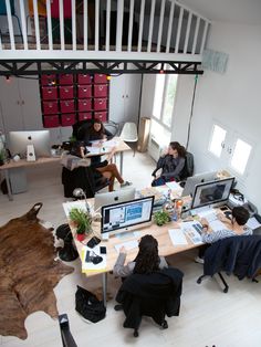 people sitting at desks in an office with computers and other items on the table