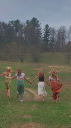 four girls running in a field holding hands