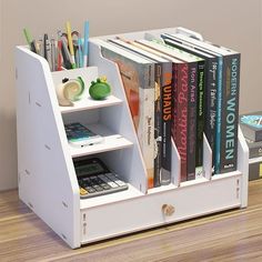 a book shelf with books, pens and pencils in it on top of a wooden floor