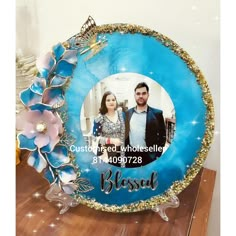 a blue and gold frame with a couple's photo in the center, surrounded by flowers