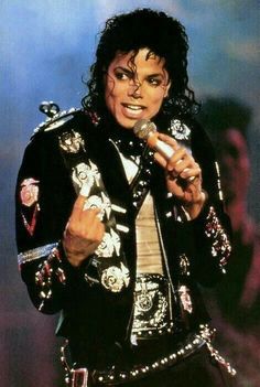 michael jackson singing into a microphone with his hair in the air and wearing an elaborate jacket