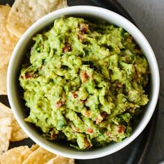 a bowl filled with guacamole surrounded by tortilla chips