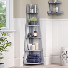 a corner shelf with towels, candles and other items on it in a white room