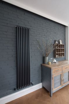 an image of a room with grey brick wall and wooden table in front of the radiator