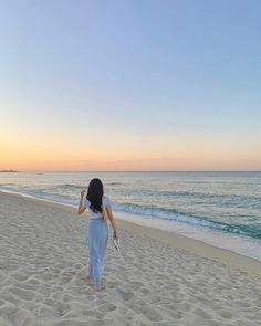 a woman standing on top of a sandy beach next to the ocean