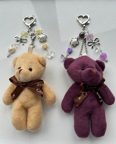 two teddy bears are sitting next to each other with key chains hanging from their ears