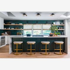 a kitchen with three stools in front of the counter and an island that has plants on it