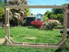 a wooden frame sitting on top of a lush green field in front of a house