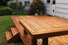 a wooden picnic table sitting on top of a lush green field next to a house