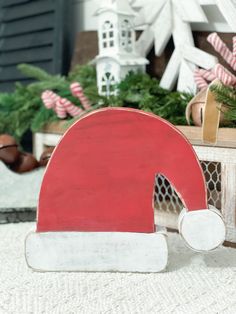 a red and white wooden sign sitting on top of a floor next to christmas decorations