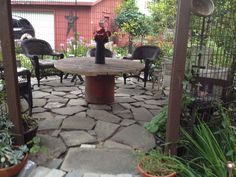 a table and chairs in a small garden area with stone pavers around the table