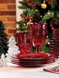 a table set for christmas with red glassware