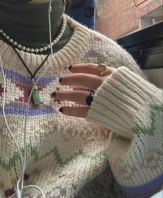 a woman with her hands on the neck of a sweater and earphones attached to her hand