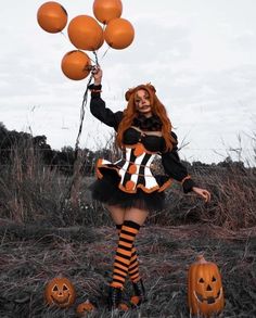 a woman dressed up as a witch with pumpkins in her hand and balloons in the air