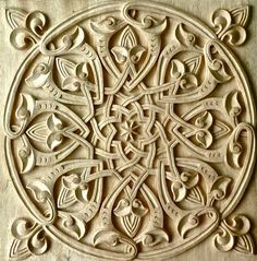 an intricately carved design on the side of a wooden panel with leaves and flowers