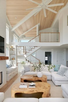 a living room filled with white furniture and a fire place in front of a flat screen tv