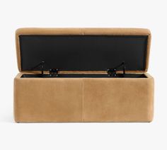 a tan leather storage bench with two black handles