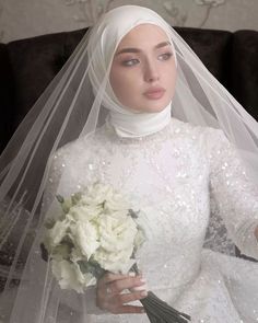 a woman wearing a white veil and holding a bouquet of flowers in her right hand