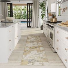 a kitchen with white cabinets and an area rug on the floor next to the stove