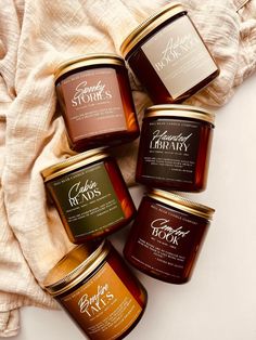 four jars of jams sitting on top of a white cloth next to each other