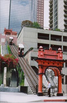 a man standing in front of a red gate with stairs leading up to the top