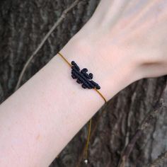 a woman's arm wearing a bracelet with black seed beads and a gold chain