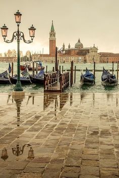 several gondolas are docked in the water near a light pole and street lamp