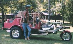 a man standing next to a red truck with a motorcycle attached to it's back