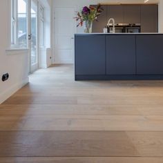 an empty kitchen with wooden floors and white walls, along with blue cabinetry on the wall