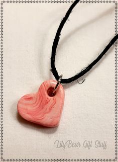 a pink heart shaped ceramic pendant on a black cord with an inscription that reads lily bear gift stuff