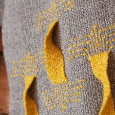 a close up of a knitted blanket with holes in the middle and yellow trim