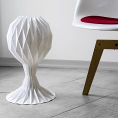 a white chair sitting next to a table with a vase on it's side