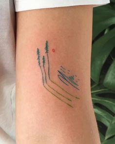 a person with a tattoo on their arm that has skis and trees in it