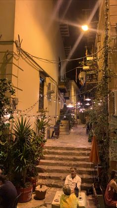 people sitting on the steps in an alleyway at night