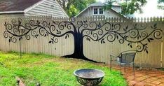 a tree painted on the side of a fence with a chair in front of it