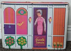 an image of a doll in the door of a house that is painted pink and purple