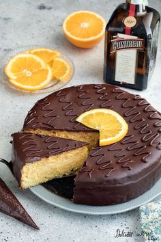 there is a chocolate cake with orange slices on the plate and a bottle of rum in the background