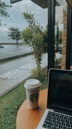 a laptop computer sitting on top of a wooden table next to a cup of coffee