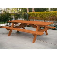 a wooden picnic table sitting on top of a cement floor next to a fenced in area