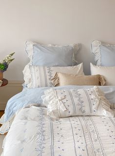 a bed with blue and white linens in a bedroom next to a table filled with flowers