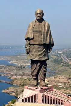 the statue of buddha is on top of a hill with water and land in the background