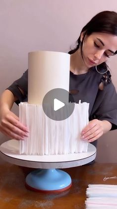 a woman is making a cake with white frosting on it and holding the base