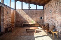 a room with brick walls and wooden furniture in the center, along with large windows