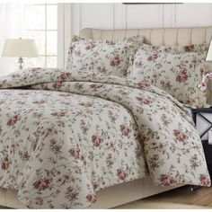 a bed with floral comforter and pillows in a room