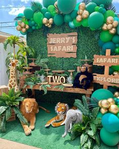 there are many animals on display at this zoo themed birthday party that is decorated with green and gold balloons